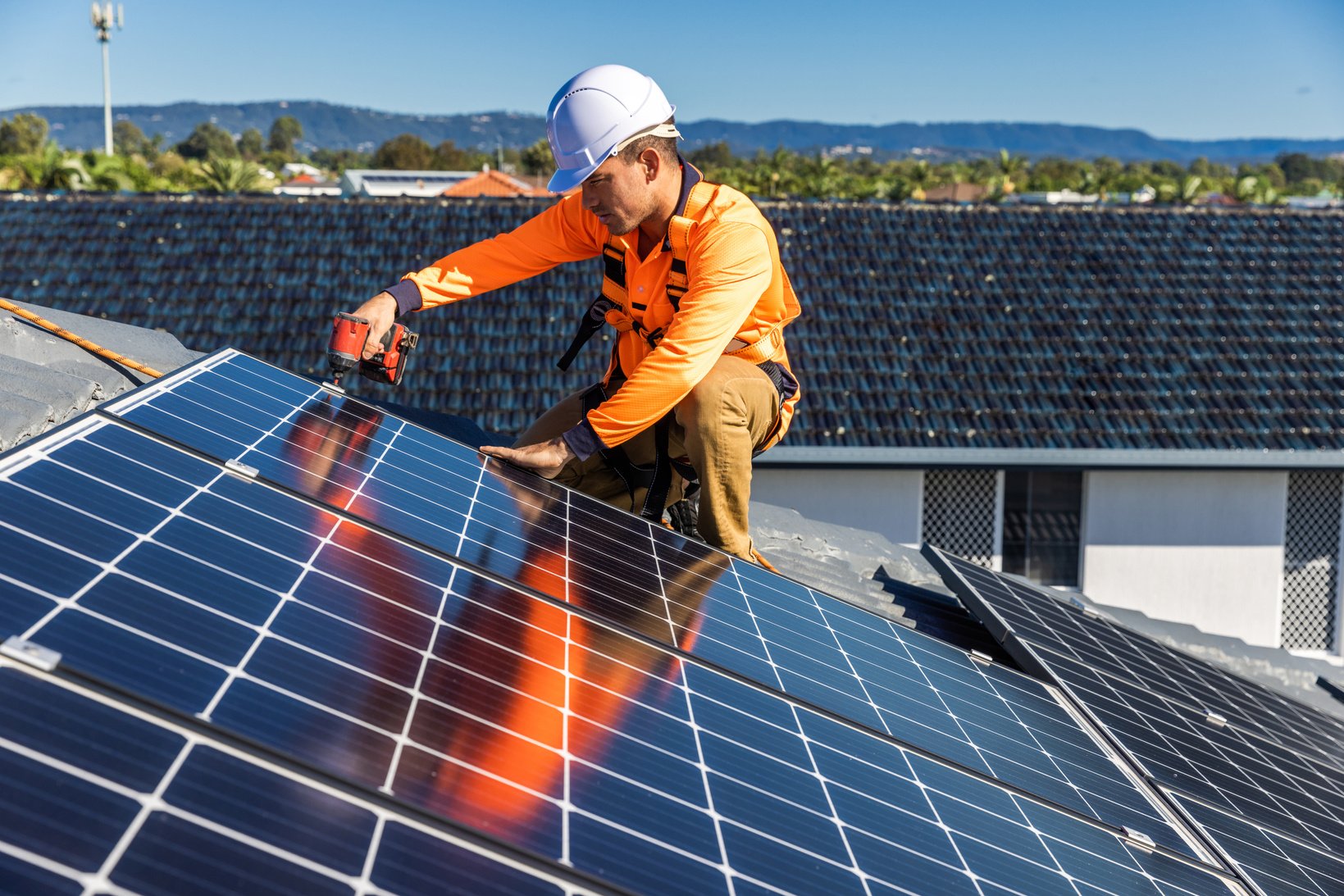 Solar panel technician with drill installing solar panels