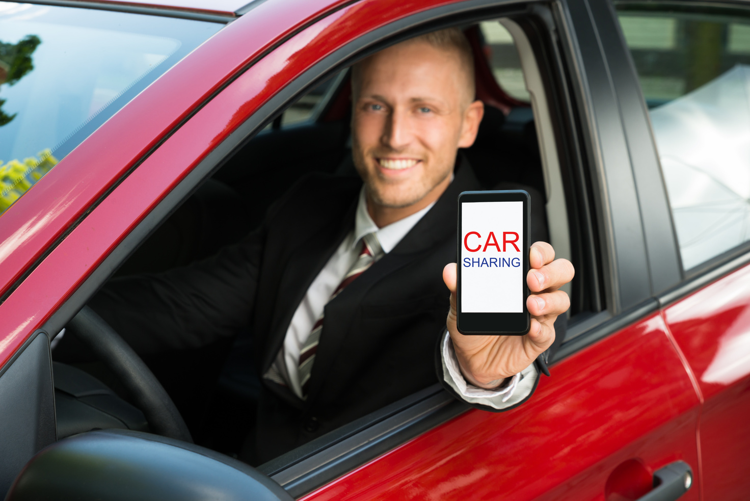 Businessman Showing Cellphone With Car Sharing Text On Screen